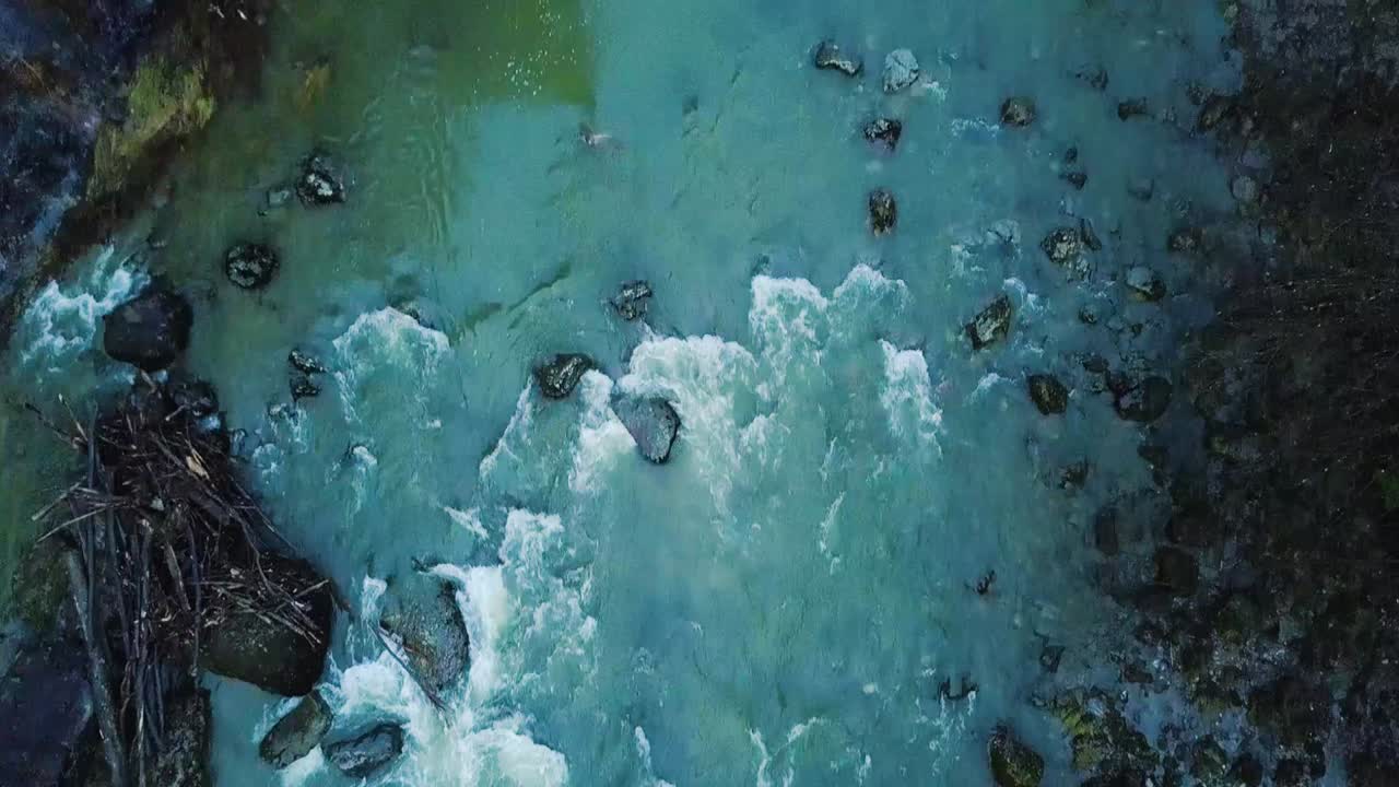 primero una toma desde arriba de un río peligroso, la cámara se inclina lentamente hacia un puente muy alto