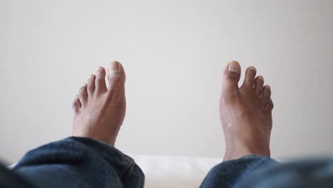 person sitting with bare feet on white sofa