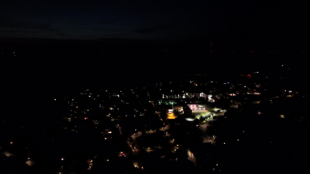 Illuminated hospital building and lighting streets of American neighborhood at nigh. Aerial forward flight. Driving cars on highway in distance. Wide shot. Peaceful and quiet atmosphere at nightscape