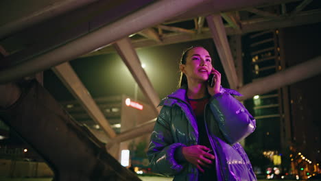 carefree woman calling standing street at night lights. girl talking cellphone.