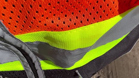 close-up macro of a hi viz safety vest moving up the vest in bright daylight