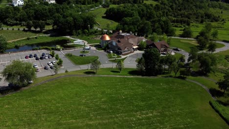 Drone-flying-over-a-banquet-house-for-celebrations-and-weddings,-surrounded-by-green-land-and-trees