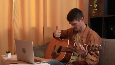hombre tocando la guitarra acústica en casa