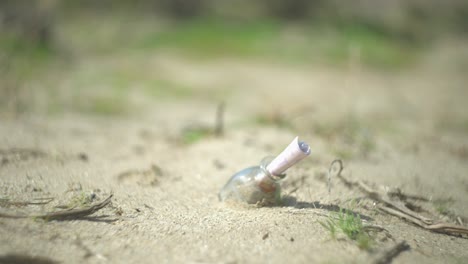 una chica caminando más allá de una botella en el suelo en el desierto de arena con una nota dentro de ella como los estantes de la cámara se centran