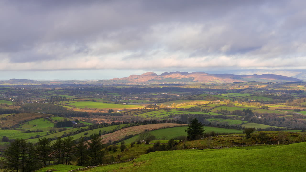 Timelapse of rural nature farmland with hills in distance during sunny day viewed from Carrowkeel in county Sligo in Ireland