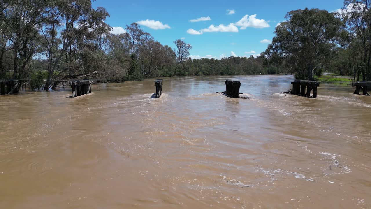 dron del río goulburn inundado con aguas rápidas pasando por un viejo puente