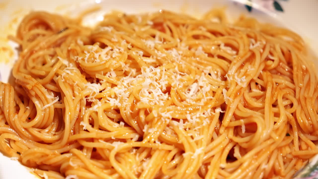 Spaghetti with sausage on a dish and adding cheese