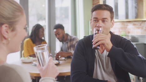 smiling young couple on date enjoying pizza in restaurant together making a toast