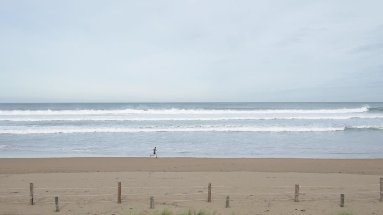 deportista en ropa activa corriendo en una playa solitaria