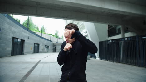 fighter man training boxing punch on urban street. closeup man boxing outdoor