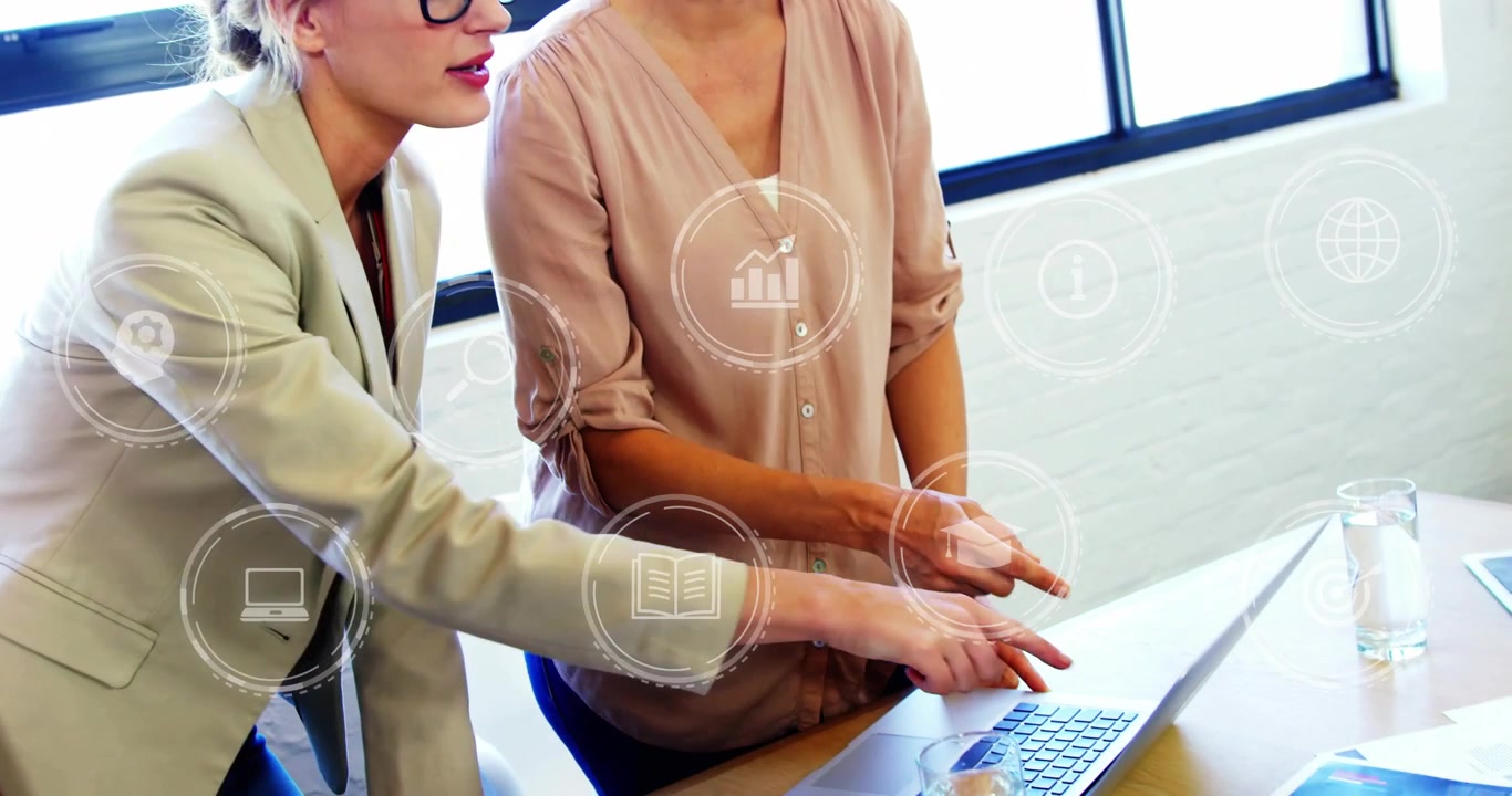 Donne che indicano un laptop, digitando sulla tastiera per preparare una presentazione aziendale, mentre icone appaiono sopra il laptop.