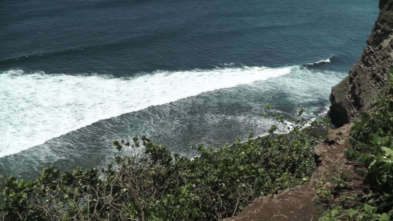 L'inquadratura dall'alto della grande onda bianca che rifluisce nell'oceano blu, panoramica a sinistra.