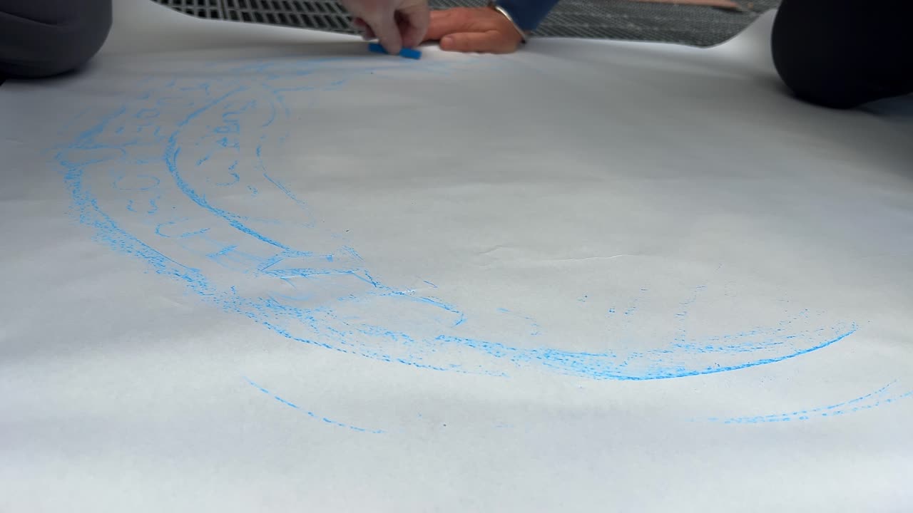 Street level view: Artists trace manhole cover on paper with charcoal