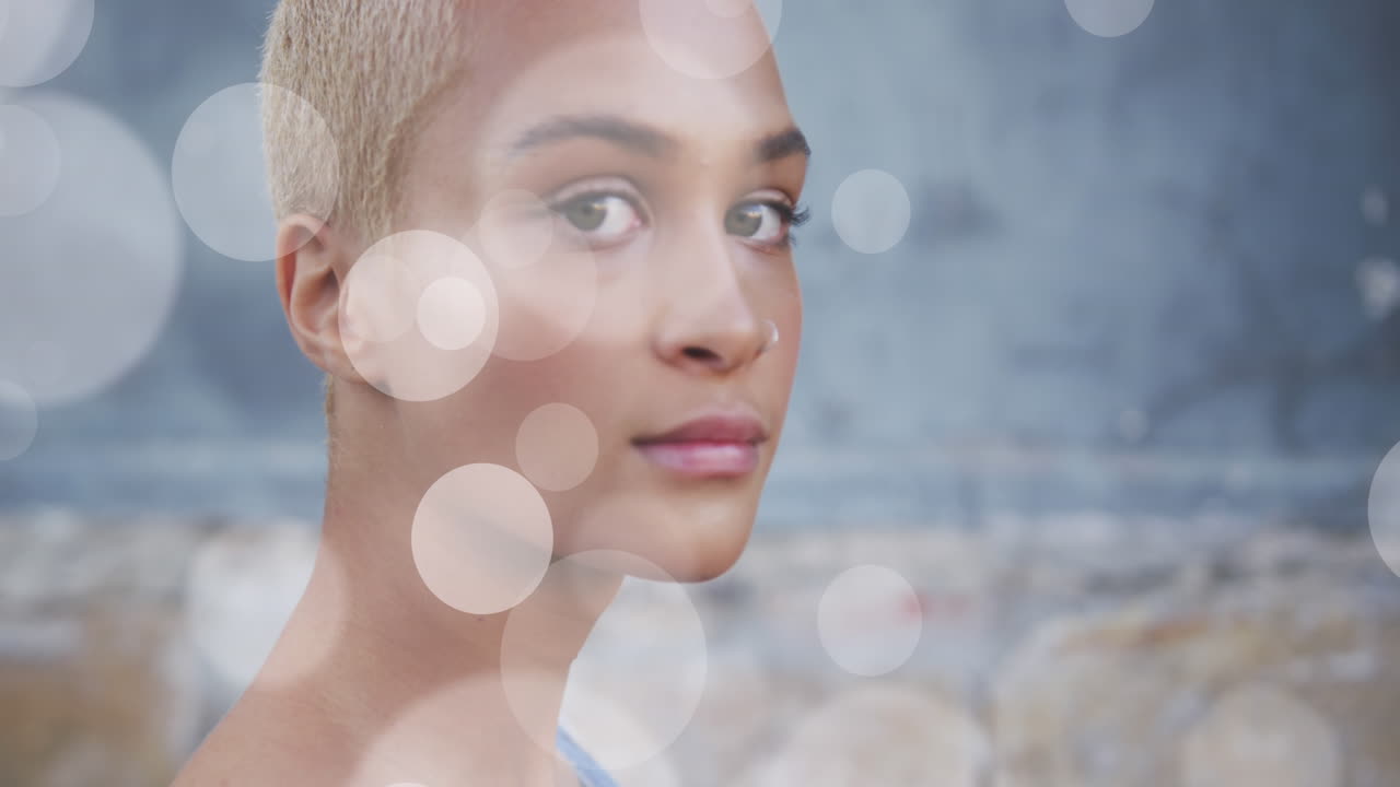 Animation of light spots over biracial woman smiling
