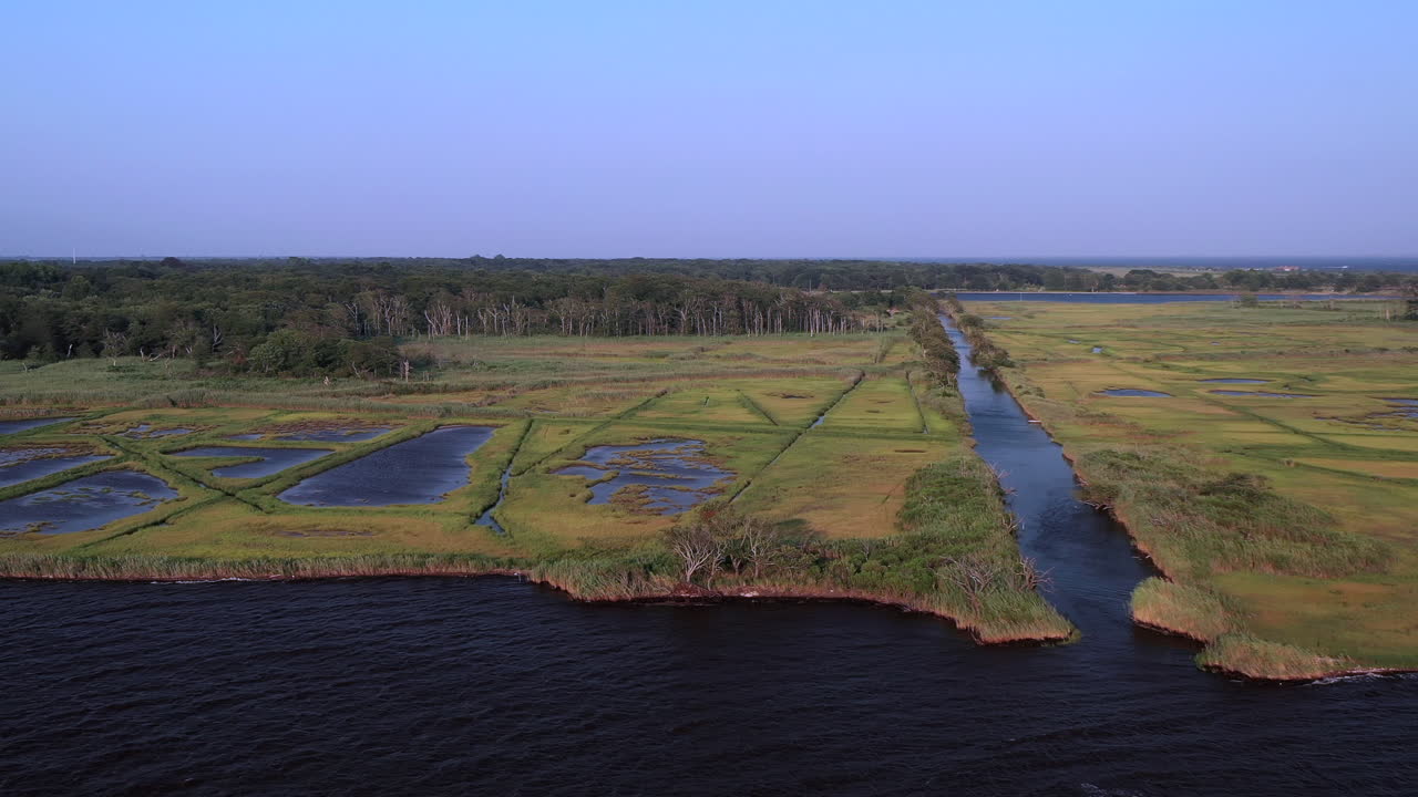 Una lenta panoramica aerea verso destra alla Marina di East Islip - Parco, sopra l'acqua, che risale il lungo canale della zona paludosa al tramonto