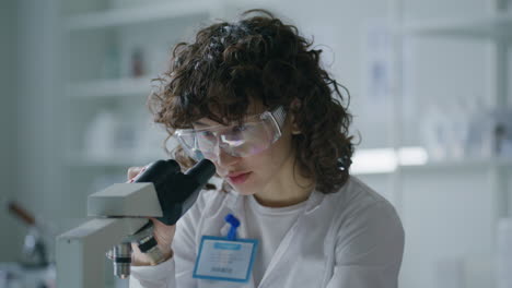 female laboratory technician performing microscopic examination