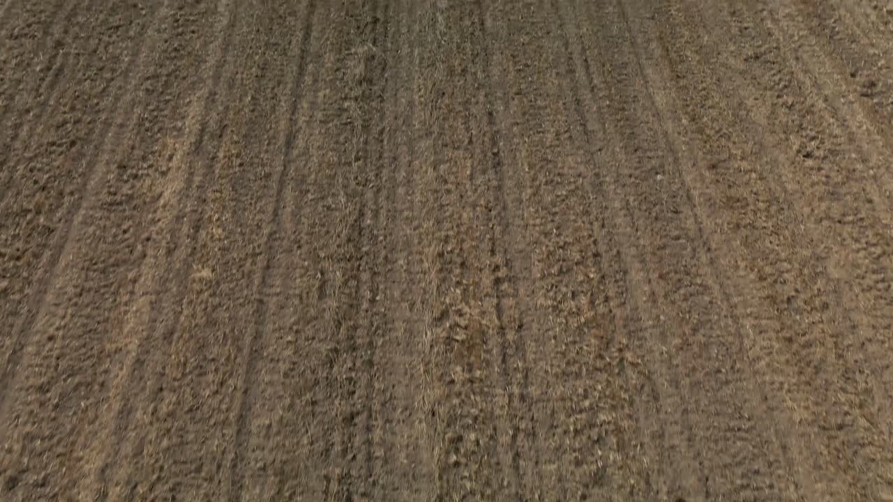 Zenital aerial view of the uncultivated cropland, as it slowly looks up to see the big mountains on the horizon
