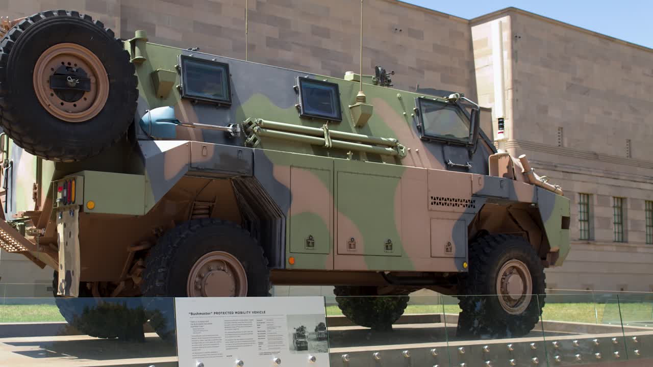 Statisk lavvinkelbilde av et kamuflert militært transportkjøretøy parkert utenfor en steinbygning