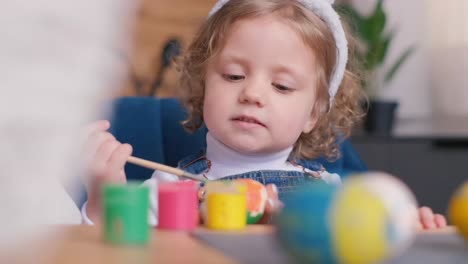 little child painting easter eggs