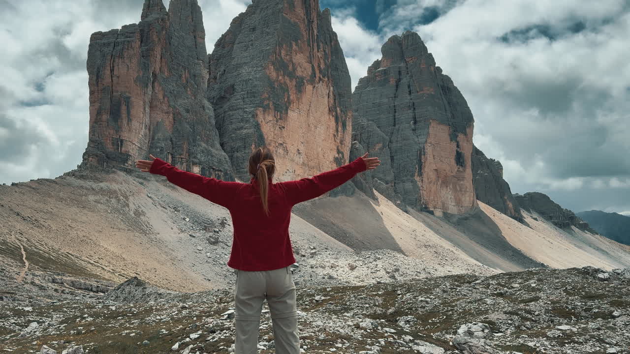 woman standing with arms outstretched enjoying the mountain view of the Tre Cime di Lavaredo