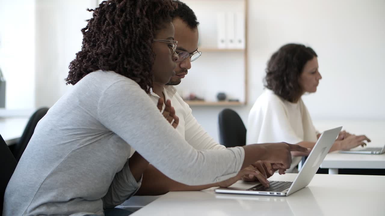 Side view of concentrated employees working with laptop