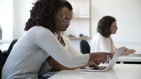 side view of concentrated employees working with laptop