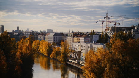 golden fall colors line canal river with buildings and cranes behind in spittelau vienna austria