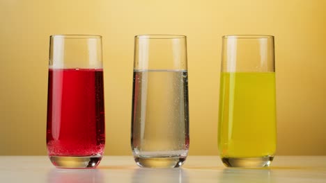 three glasses of different colored liquids