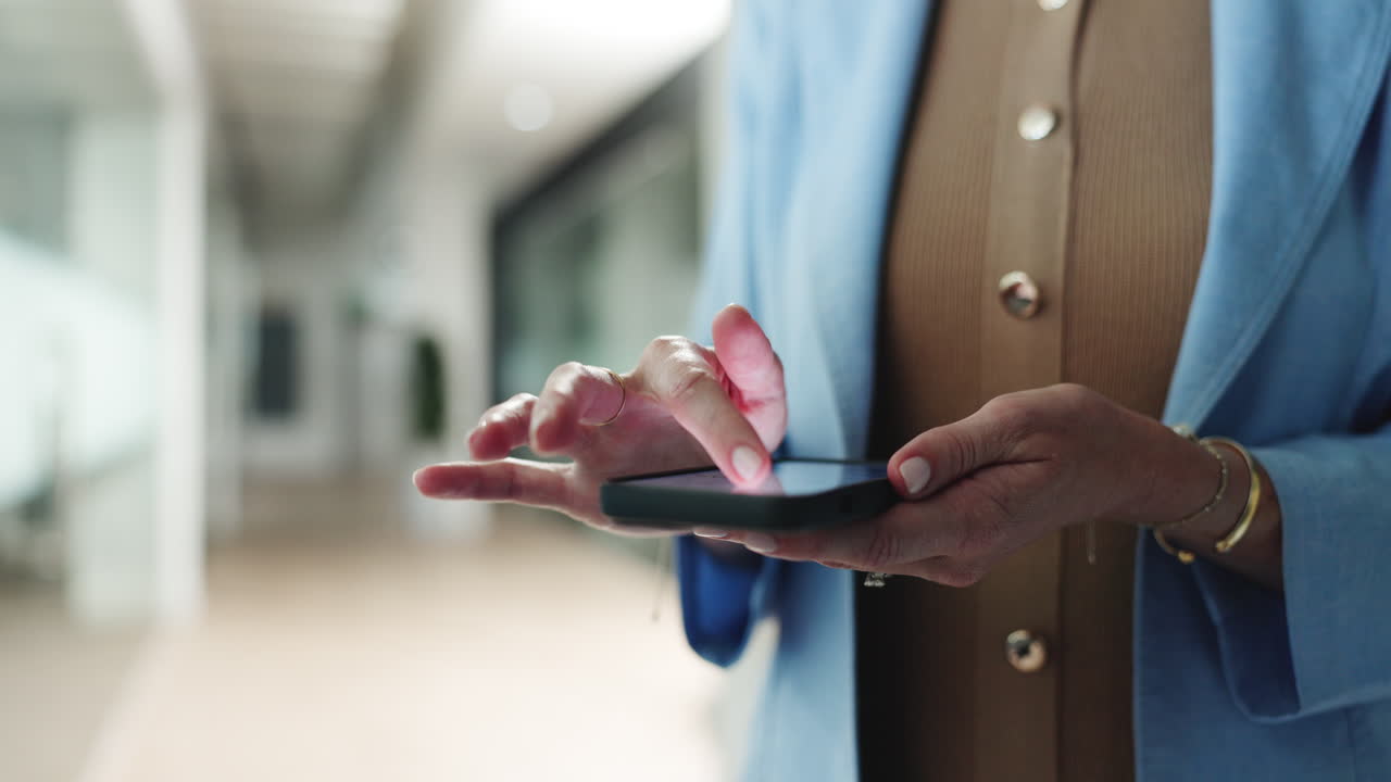 Close-up of Woman's Hands Tapping on a Smartphone in an Office