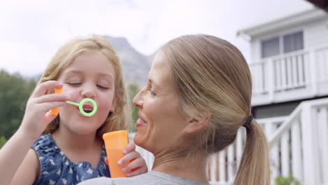 Mother-and-Daughter-blowing-bubbles-in-the-yard-happy-family-home