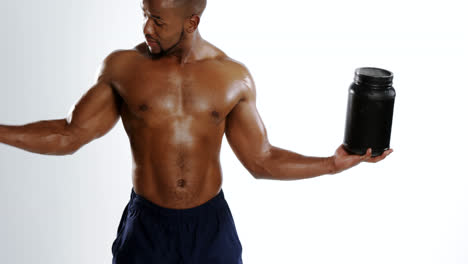 musculoso sonriente sosteniendo una botella de proteínas