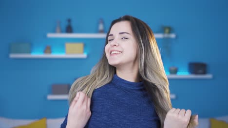una joven feliz y alegre soplando su cabello y sonriendo a la cámara.