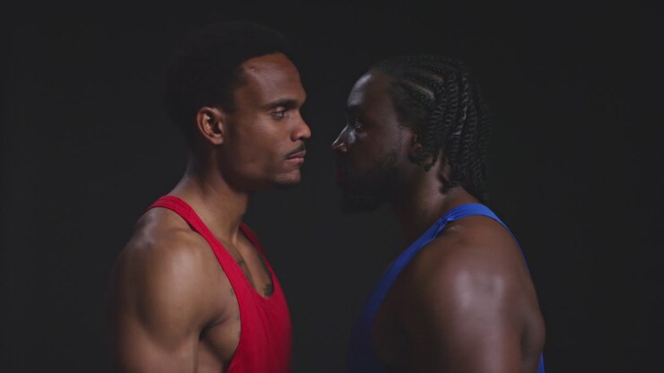 Primo piano di due pugili che si fronteggiano prima di un incontro di boxe, fissando l'avversario di profilo su sfondo nero 1