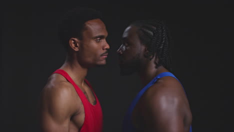 cerca de dos boxeadores masculinos que se enfrentan cara a cara antes de un partido de boxeo mirando fijamente al oponente de perfil contra un fondo negro 1