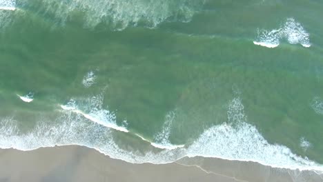 Vista-Aérea-De-Arriba-Hacia-Abajo-De-Las-Olas-Del-Mar-Rompiendo-En-La-Costa-Arenosa