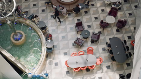 an overhead view of a bustling mall caf area featuring a water fountain, various tables, chairs, and people engaged in different activities