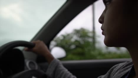 Close-up-of-young-Asian-woman-driving-car-confidently-with-calm-face,-side-angle-shot