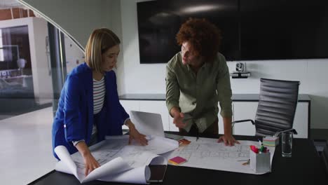 diverse male and female business colleagues in discussion at work looking at technical drawing