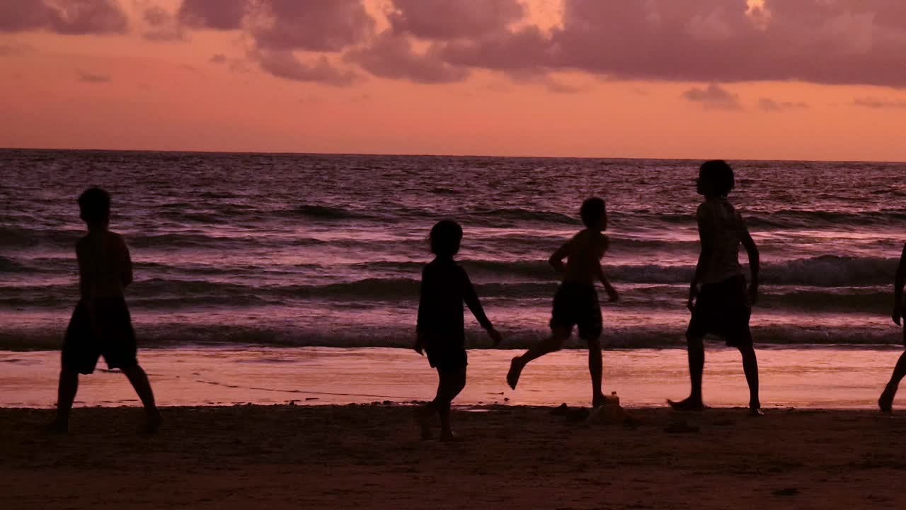 Kids playing on the beach at sunset