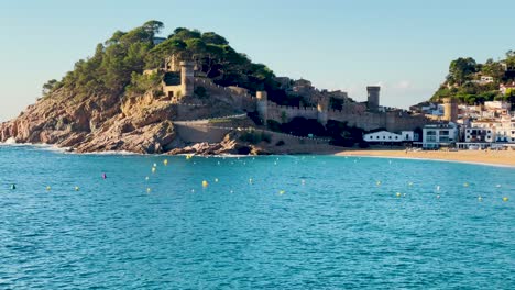 Tossa-de-Mar-bay-seen-from-the-castle-to-the-beach-with-coarse-sand-and-turquoise-blue-sea-water-old-walled-medieval-fishing-village-Mediterranean-sea