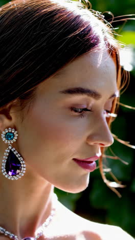 elegant woman adorned with gemstone jewelry in a lush outdoor setting