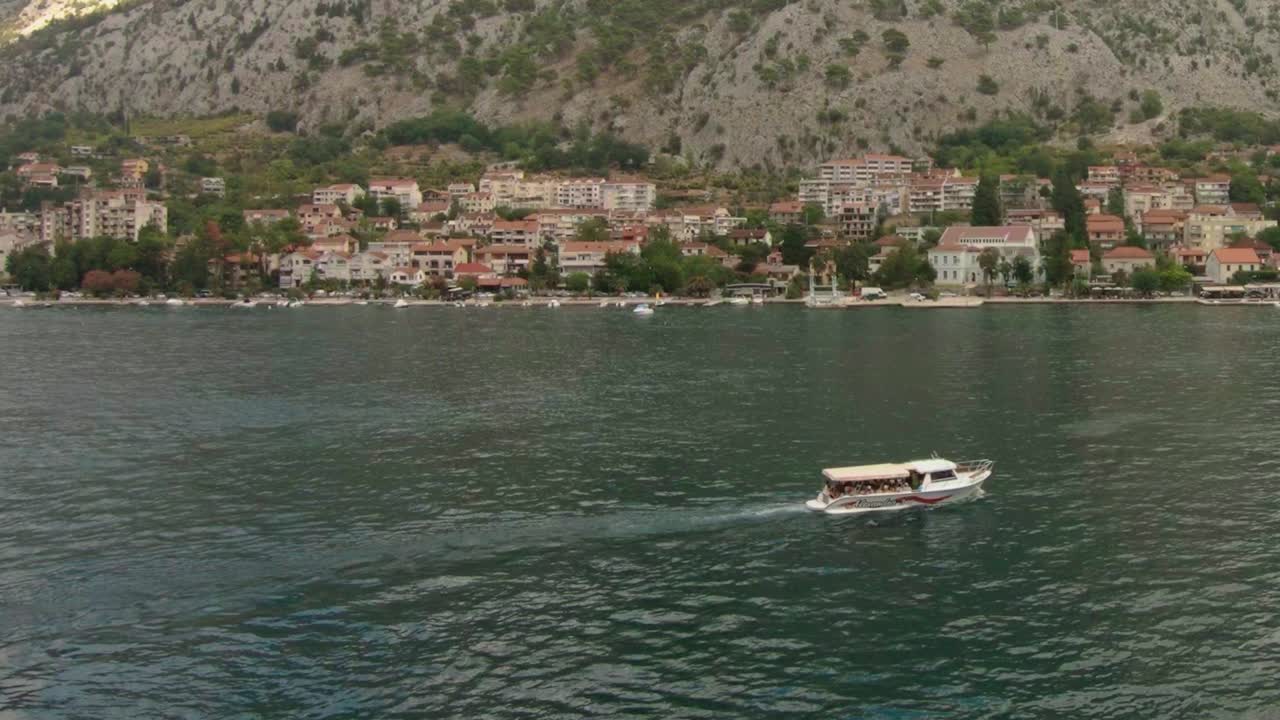 Rekaman gerak lambat perahu-perahu berlayar di lepas pantai kota pegunungan yang indah di Montenegro.