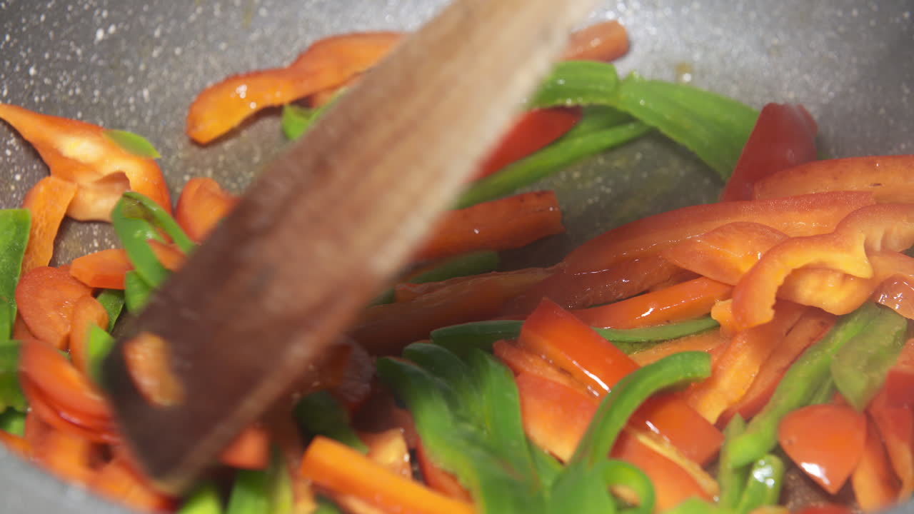 Stir-frying sliced red and green bell peppers