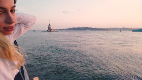 beautiful girl enjoys sunset view of bosphorus with view of maiden tower at background in istanbul