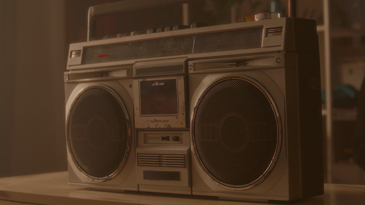 Hand Placing Audio Cassette into Vintage Boombox under Warm Light