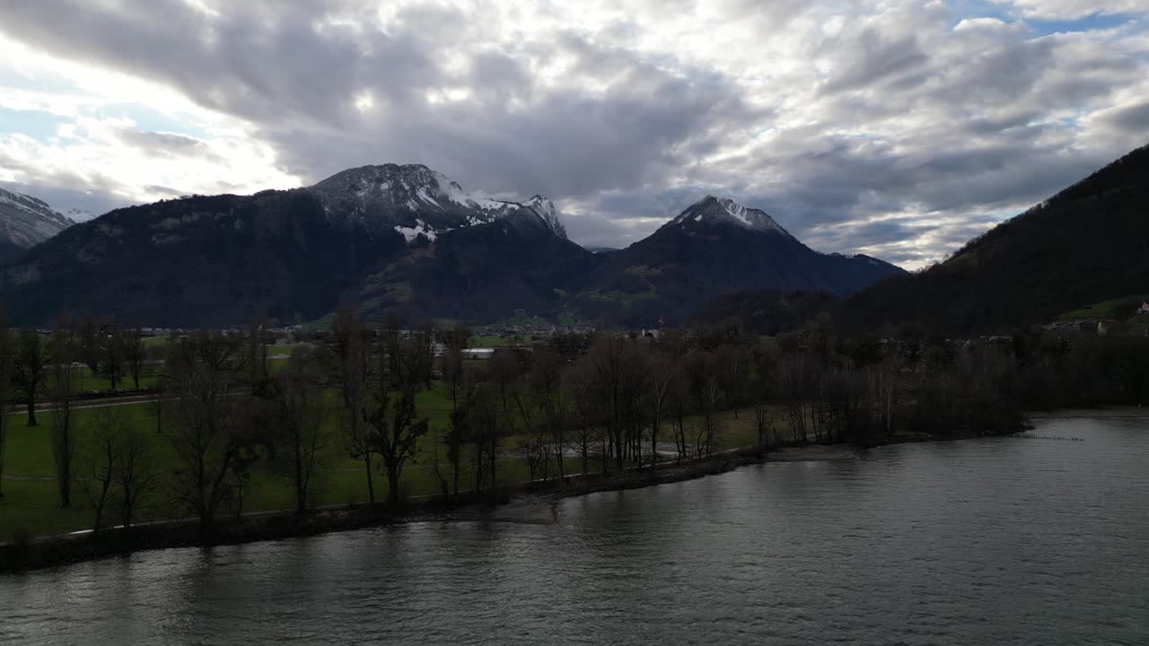 paralaje aéreo alrededor de la costa con impresionantes montañas suizas y nubes epidémicas en la distancia