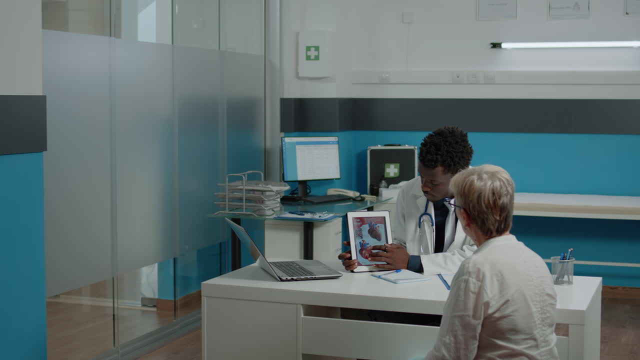 Odborník na zdravotní péči vysvětluje kardiogram na displeji tabletu