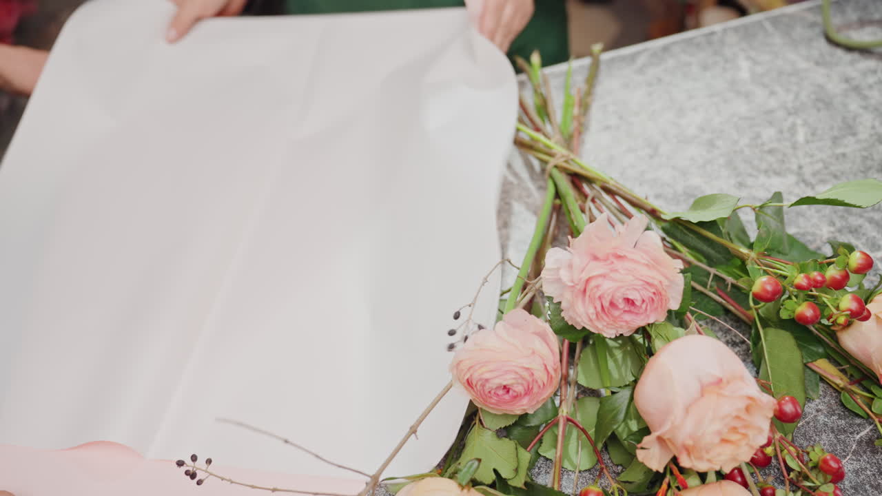 Preparing flowers with care. Carefully wrapping and presenting floral bouquet with elegance and precision. Florist delicately arranges and folds pink wrapping paper around beautiful flower collection