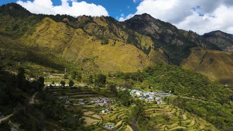 aerial drone shot of a mountain village with tiny houses scattered across the green valley.
