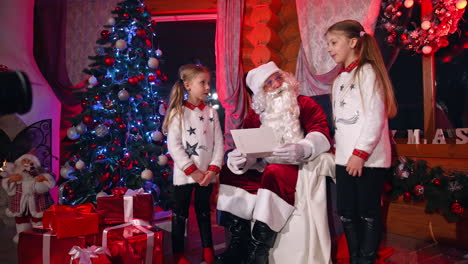sisters writing letter for santa claus. happy family with santa claus laughing and smiling